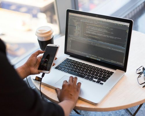 Person Holding Smartphone while using Laptop